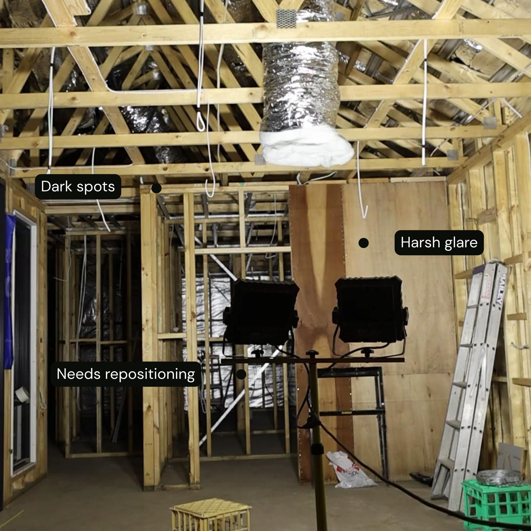 Room under construction with wooden beams and a light fixture, showing dark spots and harsh glare of floodlights