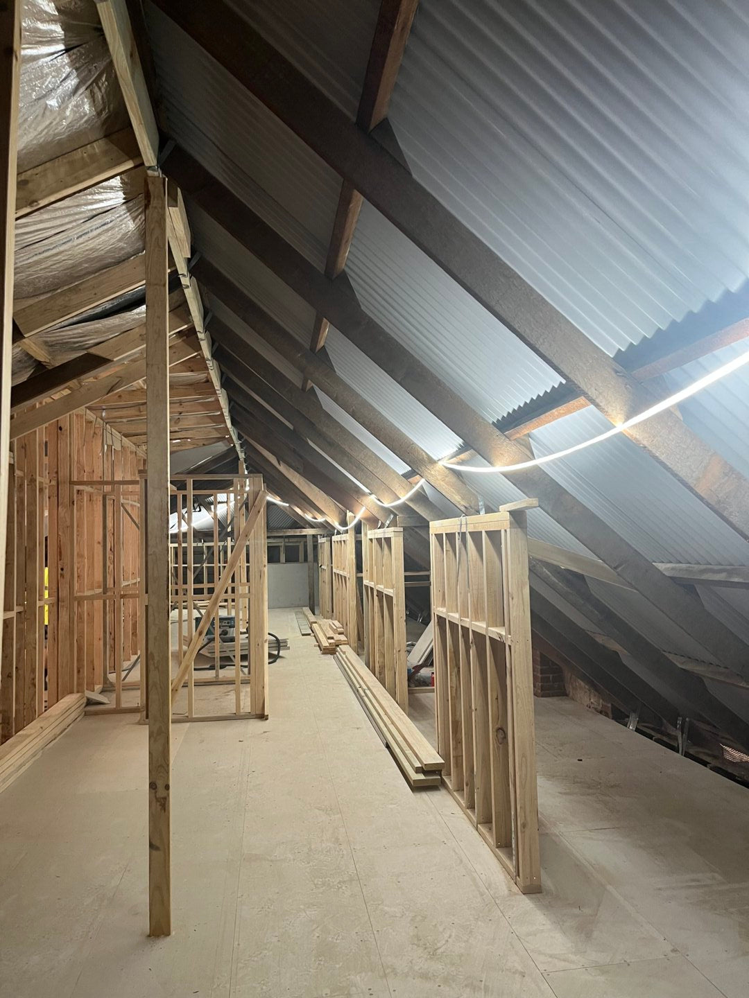 Indoor construction site with LED site light cable running through wooden beams